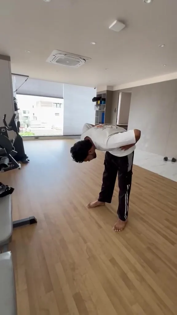 Man bends forward at the waist in an empty studio with hands behind his back