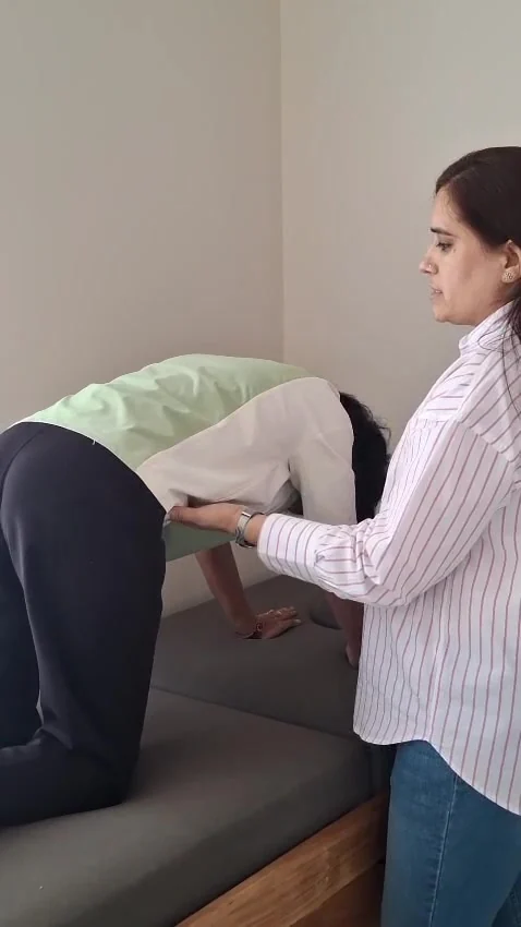 Standing woman supports the waist of a person kneeling on all fours with head hanging down