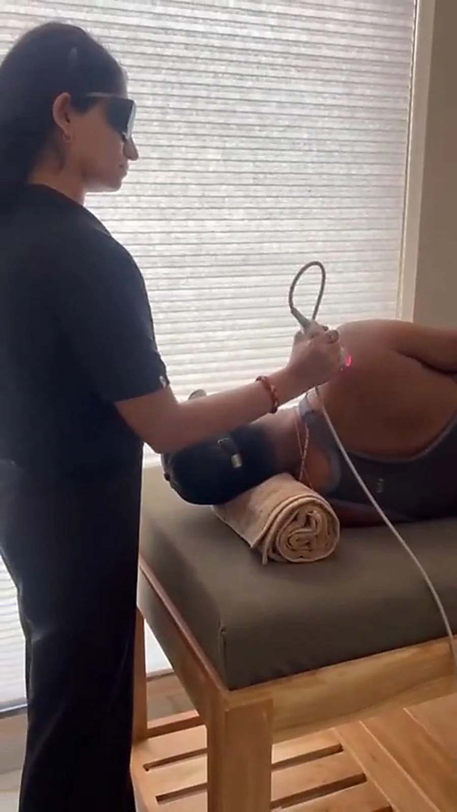 Therapist in protective eyewear applying a laser therapy probe to a patient's hip