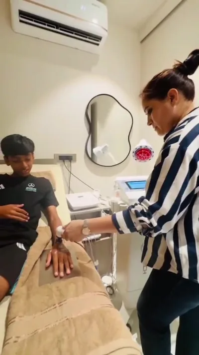 Physiotherapist applying a small cabled electrotherapy applicator to the forearm and wrist of a seated patient on a treatment couch at Trivayu Physio Center.