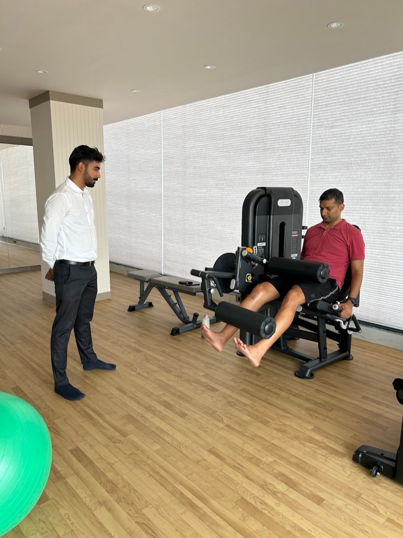 A physiotherapist supervising a patient during strength-based rehabilitation at Trivayu Physio Center